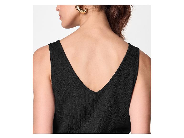 Vrouw in zwarte top met V-hals op de rug en gouden oorbellen.