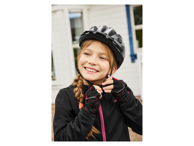 Fille souriante en veste de cyclisme Crivit noire, casque et gants.