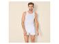 Man in wit hemd en boxershorts lachend naar de camera.