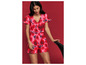 Een vrouw draagt een roze jumpsuit met rode rozenprint.