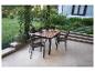 Mobilier d'extérieur avec table et chaises sur une terrasse avec jardin en arrière-plan.