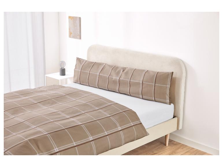 Bed met een beige hoofdbord en een geruit dekbedovertrek en kussensloop.