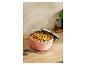 Casserole rose avec des pâtes, une bouteille d'huile et des épices sur une table en bois.
