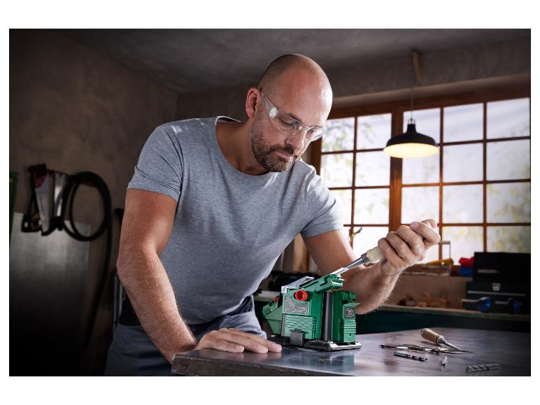 Een man scherpt een beitel op een Bosch-slijpmachine.