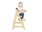 Une petite fille assise sur une chaise haute en bois.