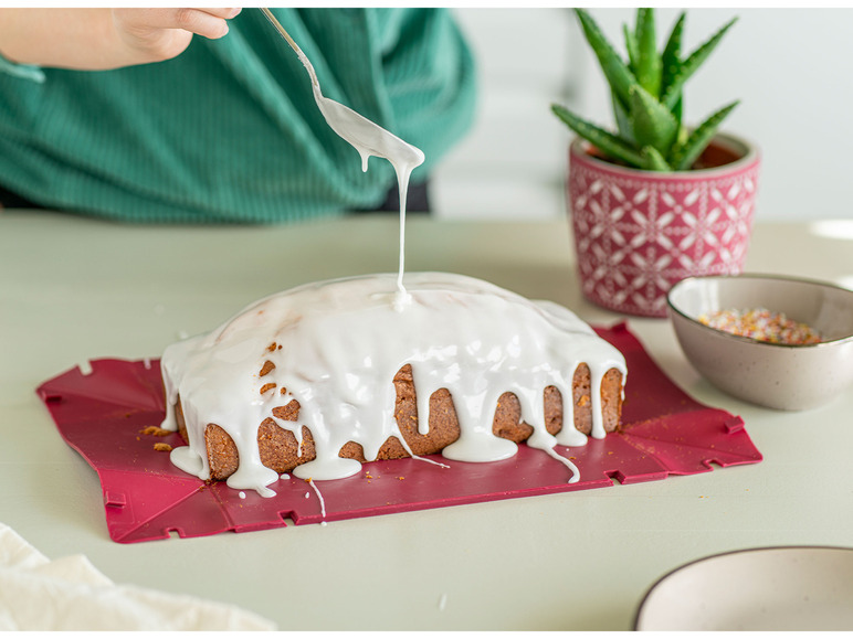 Een cake met glazuur op een rode siliconen bakmat