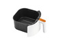 Une friteuse à air blanche avec un panier noir et une poignée orange.