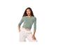 Vrouw in een groene top met lange mouwen en een witte broek met een gevlochten riem.
