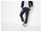 Man in donkerblauwe broek, wit T-shirt en donkerblauw overhemd.