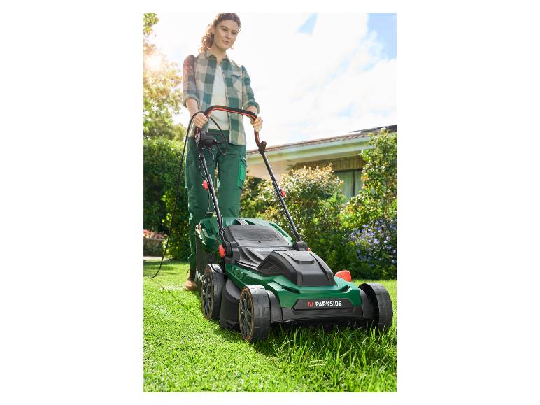 Une femme tond la pelouse avec une tondeuse à gazon verte Parkside.