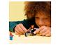 Kind speelt met speelgoedmotor en figuren op een gele achtergrond.