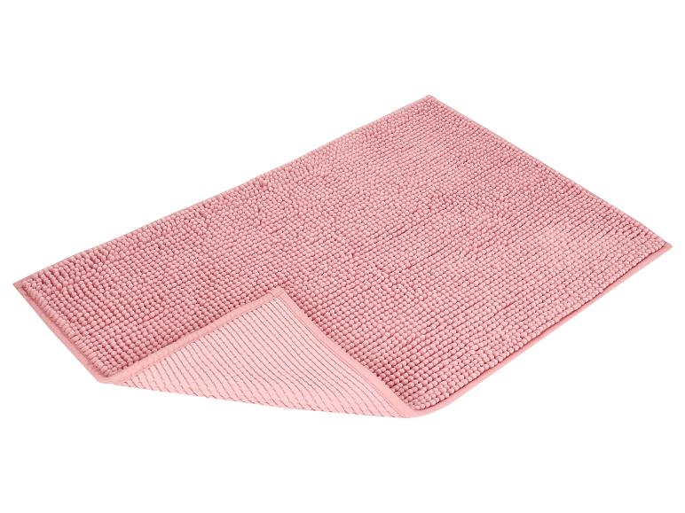 Tapis de bain rose à texture bulle, plié dans un coin.