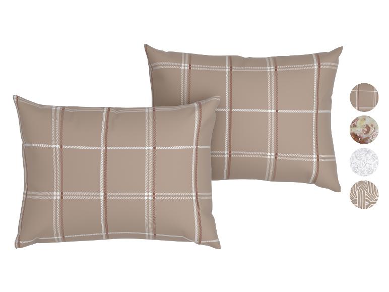 Deux oreillers à carreaux beiges, blancs et marrons, avec des échantillons de motifs sur le côté.