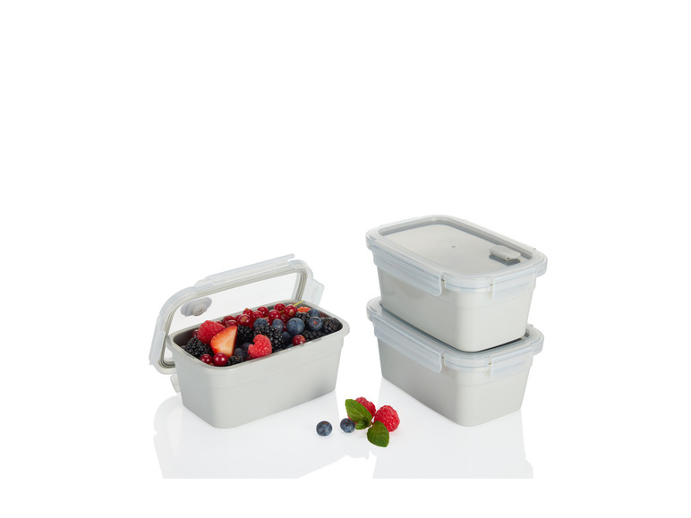 Drie grijze lunchboxen met een van de boxen gevuld met bessen.