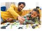 Père et fille construisant un ensemble de jouets sur le sol.