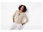 Femme en cardigan beige, haut rayé et pantalon blanc