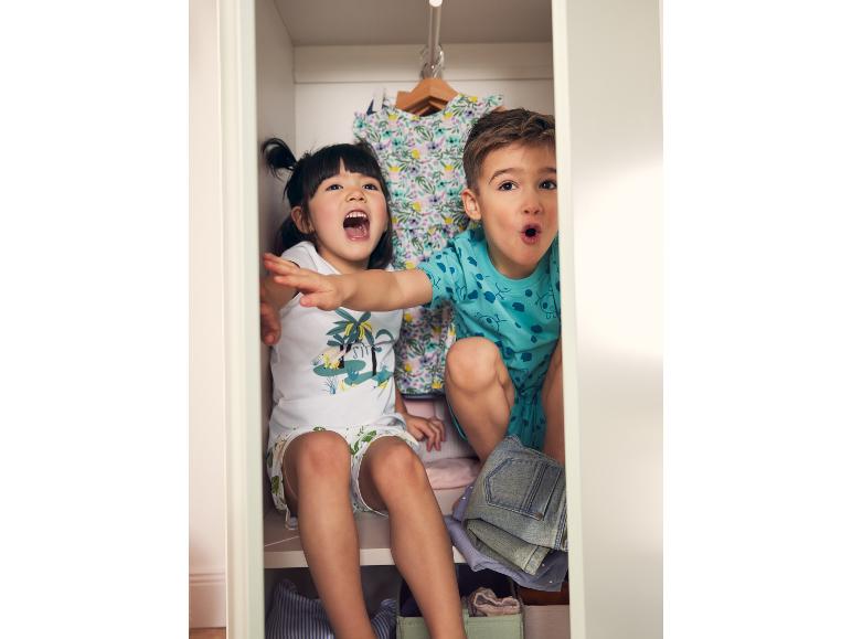 Enfants jouant à cache-cache dans un placard avec des vêtements d'été
