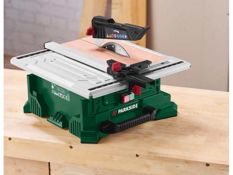 Groene tafelzaag met wit werkoppervlak op een houten tafel.