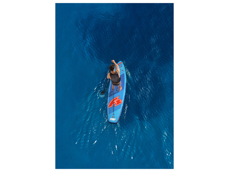 Een persoon die op een blauwe Red Paddle Co. SUP staat in de zee.