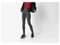 Vrouw in grijze legging, rode top en zwart jack.