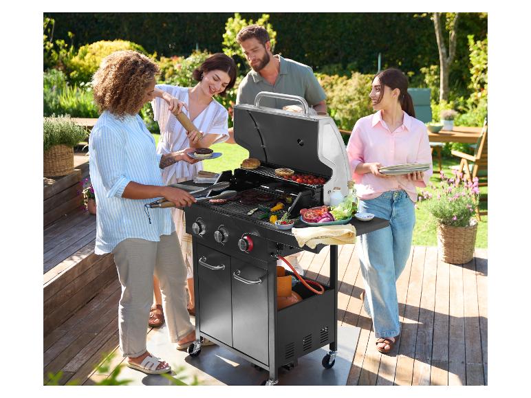 Vier vrienden barbecueën met een GRILLEMEISTER grill in een zonnige tuin.