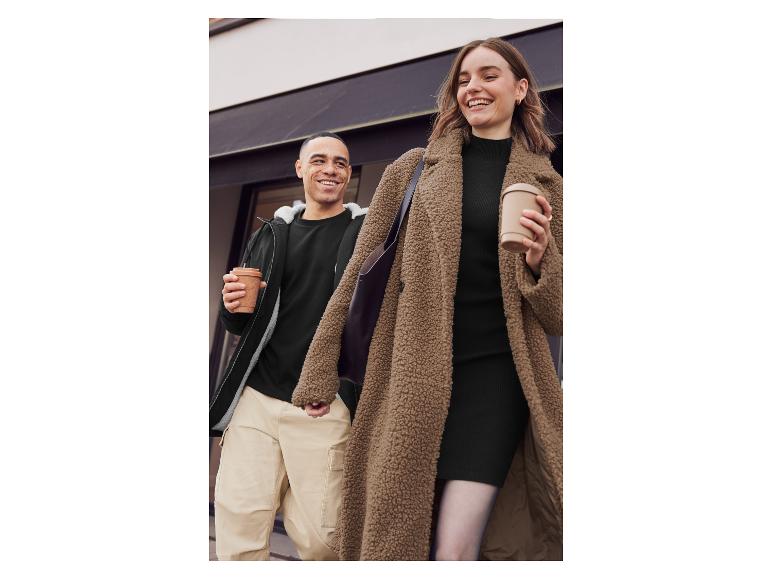 Une femme en veste en fourrure teddy marron et un homme en veste noire marchent ensemble dans la rue.