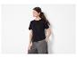 Femme en T-shirt noir et pantalon gris, main dans la poche