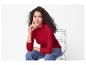 Femme souriante aux cheveux bouclés, portant un haut rouge et un jean, assise sur une chaise.