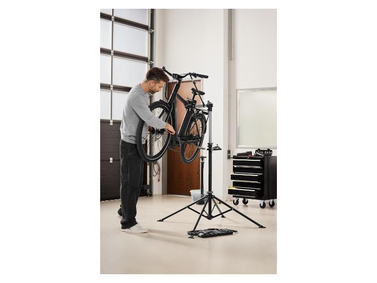 Een man werkt aan een zwarte e-bike op een reparatiestandaard.