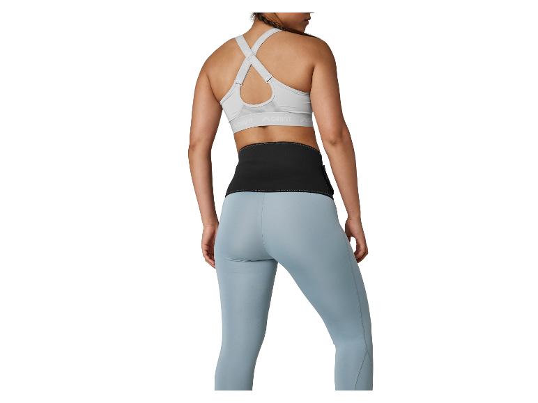Femme en brassière de sport grise, ceinture de fitness noire et leggings bleus, vue arrière.