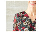 Een zwarte blouse met rode bloemenprint en ruches.
