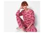 Vrouw in een roze pyjamaset met kersttekkelprint.