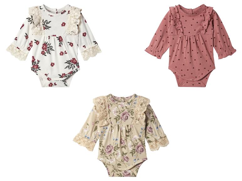 Drie rompertjes met lange mouwen, twee met bloemenprint en één met hartjes.
