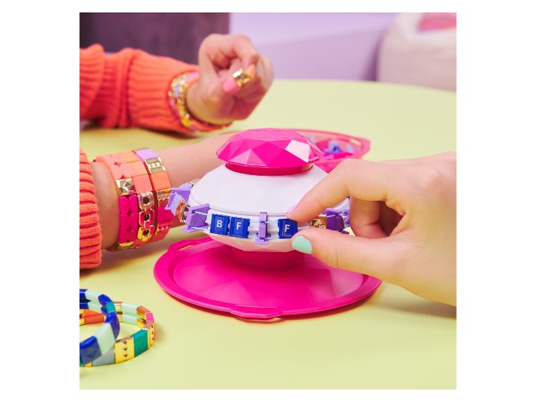 Un fabricant de bracelets rose avec des perles et une pile de bracelets colorés.