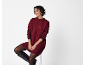 Femme souriante en robe pull bordeaux, collants noirs et bottes hautes.