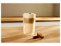 Latte macchiato in een glas met schuim en twee koekjes op een houten tafel.
