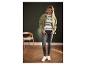 Vrouw draagt groene jas, gestreepte top, grijze jeans en witte sneakers.