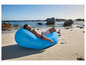 Een man relaxen op een blauwe opblaasbare loungestoel op het strand.