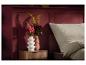 Twee moderne vazen met bloemen op een nachtkastje naast een bed.