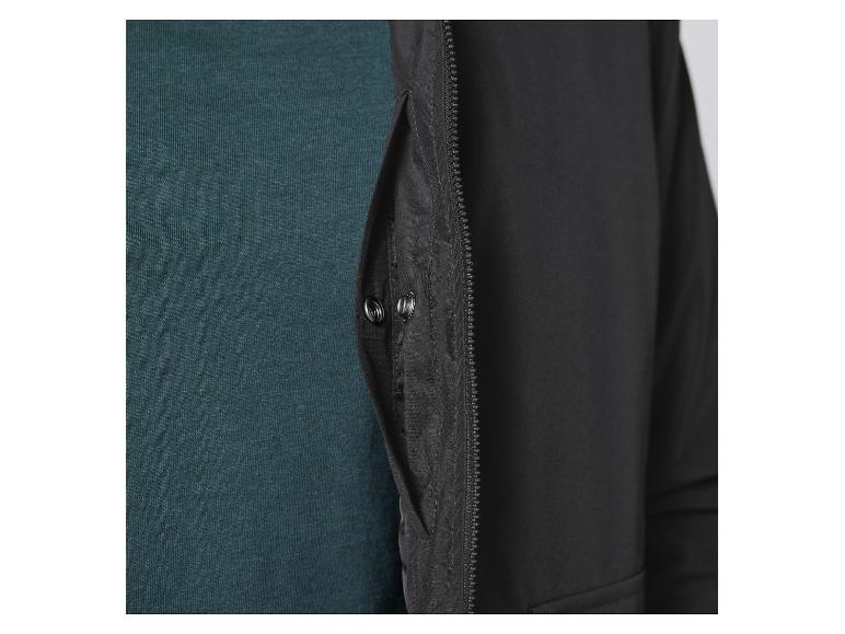 Gros plan sur une veste noire à fermeture éclair et un pull vert.