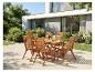 Ensemble de salle à manger de jardin en bois avec six chaises sur une terrasse près d'une maison moderne et d'un jardin.