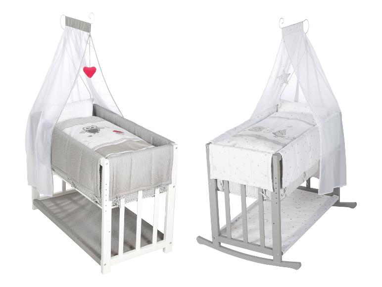 Deux lits bébé avec baldaquin, un blanc et un gris, avec literie assortie.
