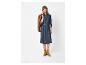 Femme en robe en jean bleue avec ceinture, veste marron et bottes en daim.