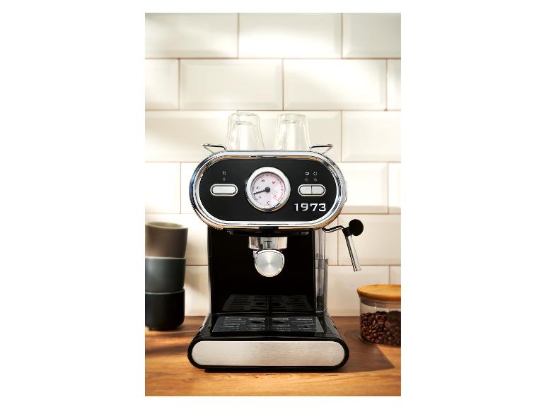 Zwart koffiezetapparaat voor een witte tegelmuur op een houten aanrecht