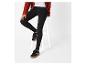 Une personne portant un cardigan rouille, un jean noir et des baskets noires.