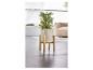 Een witte plantenpot op een houten standaard met een groene plant.