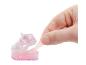 Main tirant du slime rose pailleté d'un moule transparent en forme de chaussure.