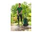 Homme nettoyant une terrasse avec un nettoyeur haute pression dans un jardin.