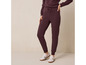 Une femme porte un pantalon de survêtement bordeaux et des baskets blanches.