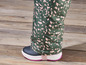 Een close-up van een groene broek met roze print en zwarte snowboots.